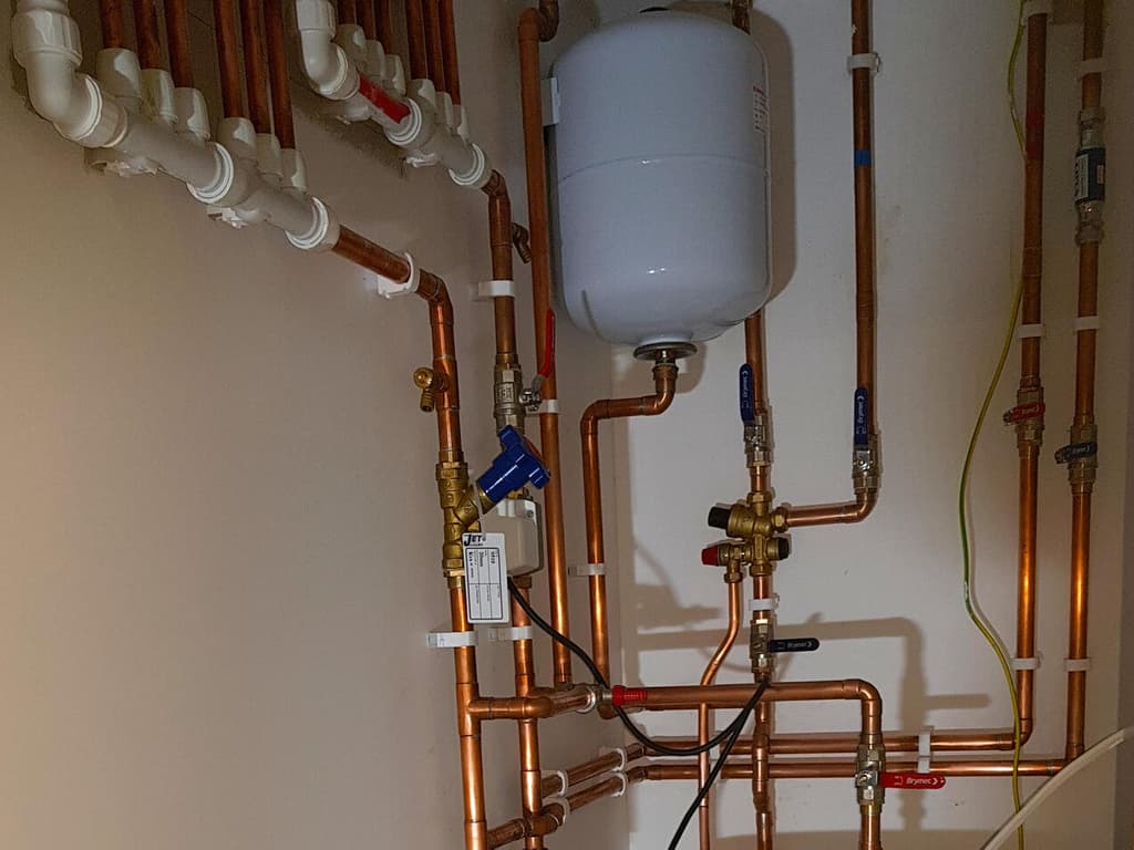Țevi de cupru trase exact în jurul unui boiler de apă caldă